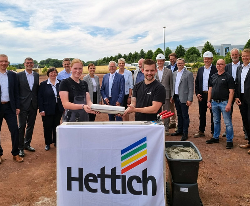 Apprentices (front, from left) Rebecca Buschkamp and Yannik Gebauer lowering the jointly made time capsule at the cornerstone laying ceremony for the new multifunctional production facility at the Kirchlengern/Bünde operating base in Germany
